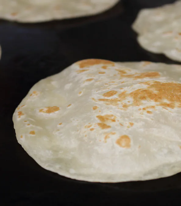 Tortilla de harina inflándose en el comal de la tortillería